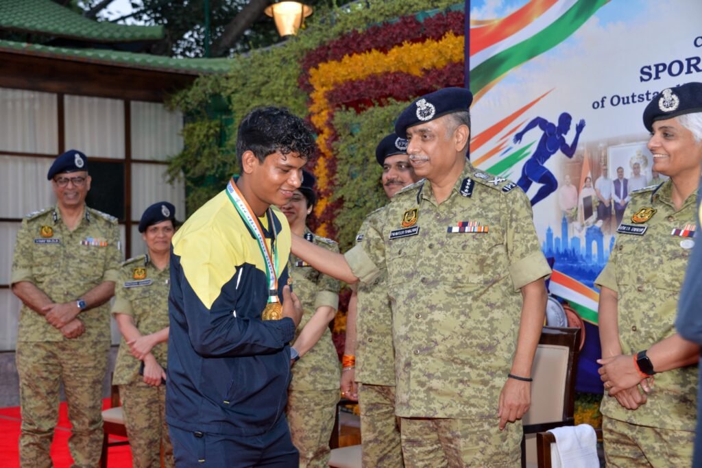 सीआईएसएफ महानिदेशक पदक पहने युवा खिलाड़ी की पीठ थपथपाते हुए, पीछे मुस्कुराते अधिकारी
